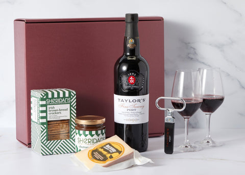 Wine gift set with Taylor's wine bottle, crackers, and cheese on a marble surface.